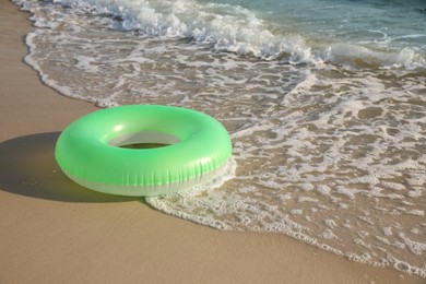 Green inflatable ring on sandy beach near sea, space for text Photo of Green inflatable ring on sandy beach near sea, space for text