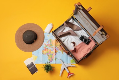 Flat lay composition with packed suitcase and travel accessories on yellow background. Summer vacation Photo of Flat lay composition with packed suitcase and travel accessories on yellow background. Summer vacation