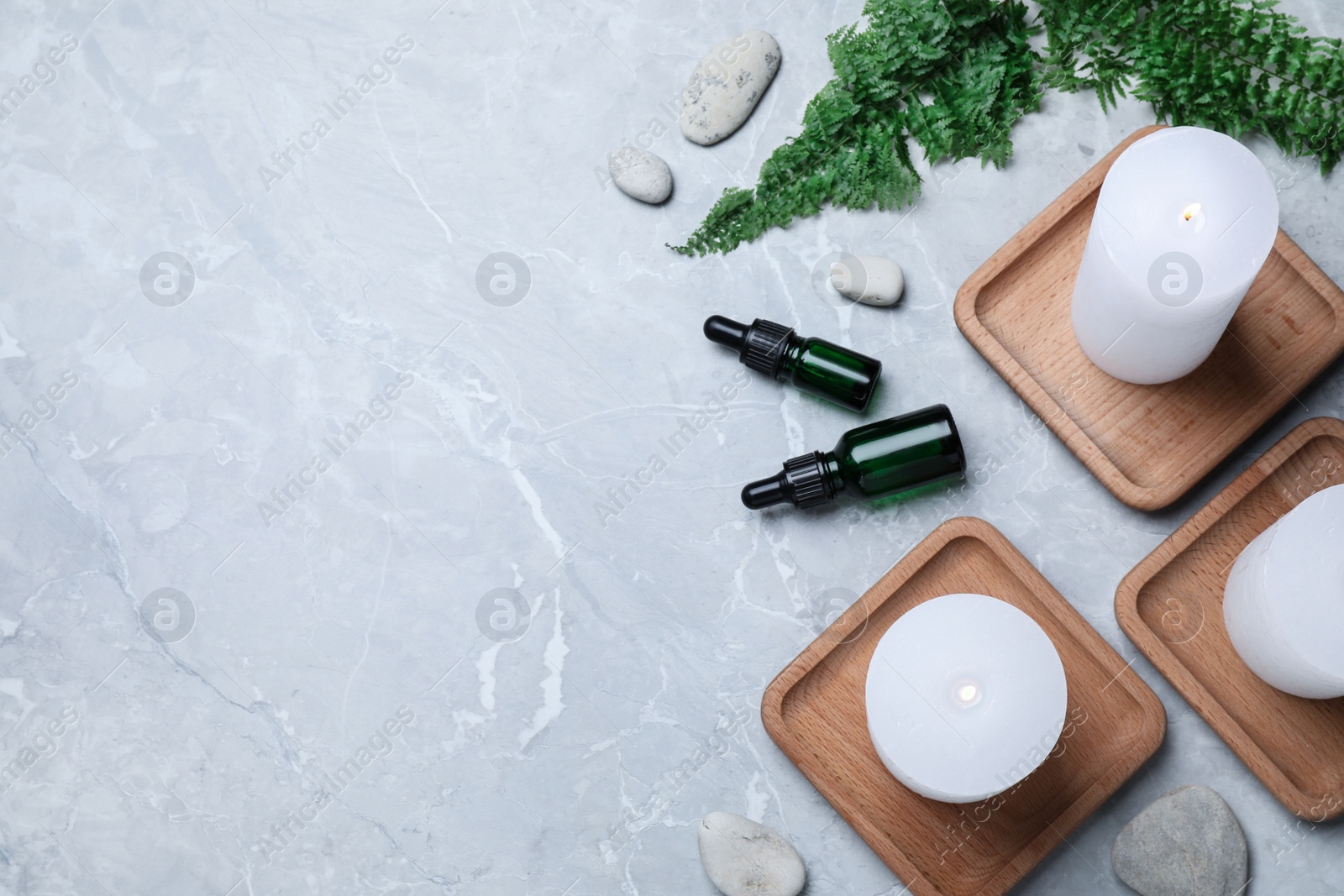 Burning candles, stones and essential oil on grey marble table, flat lay. Space for text Photo of Burning candles, stones and essential oil on grey marble table, flat lay. Space for text
