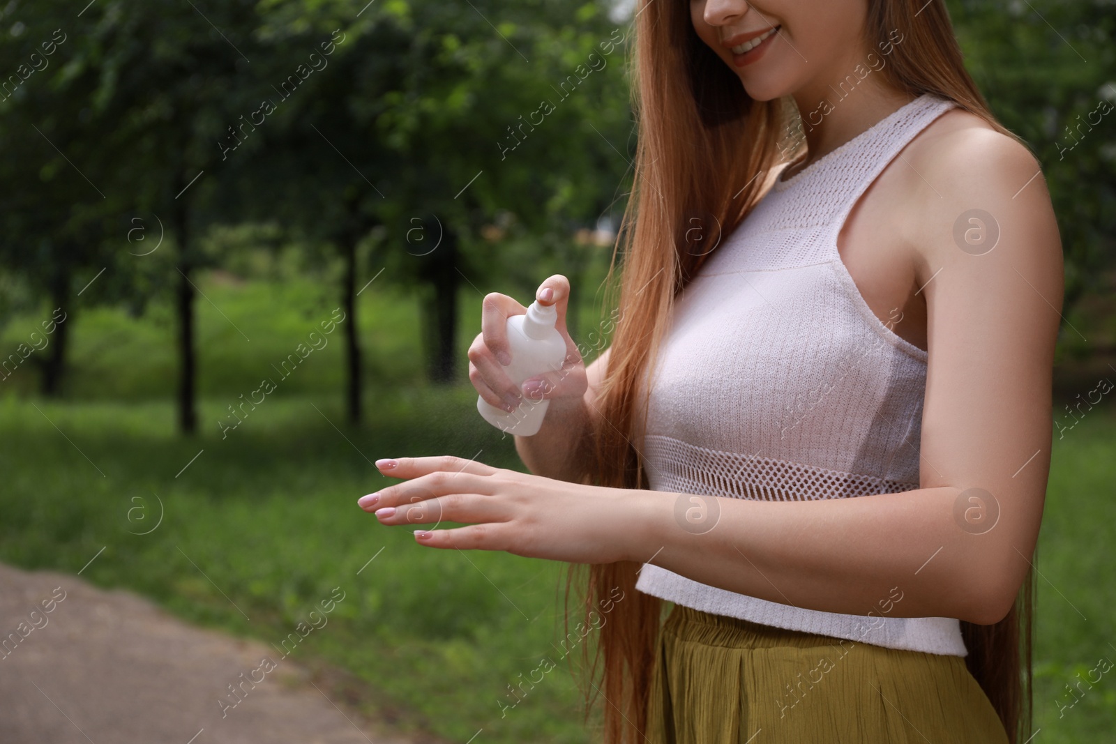 Woman applying insect repellent onto hand in park, closeup. Tick bites prevention Photo of Woman applying insect repellent onto hand in park, closeup. Tick bites prevention