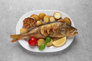 Tasty homemade roasted perch with garnish on grey table, top view. River fish Photo of Tasty homemade roasted perch with garnish on grey table, top view. River fish