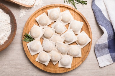 Uncooked ravioli and rosemary on white wooden table, flat lay Photo of Uncooked ravioli and rosemary on white wooden table, flat lay