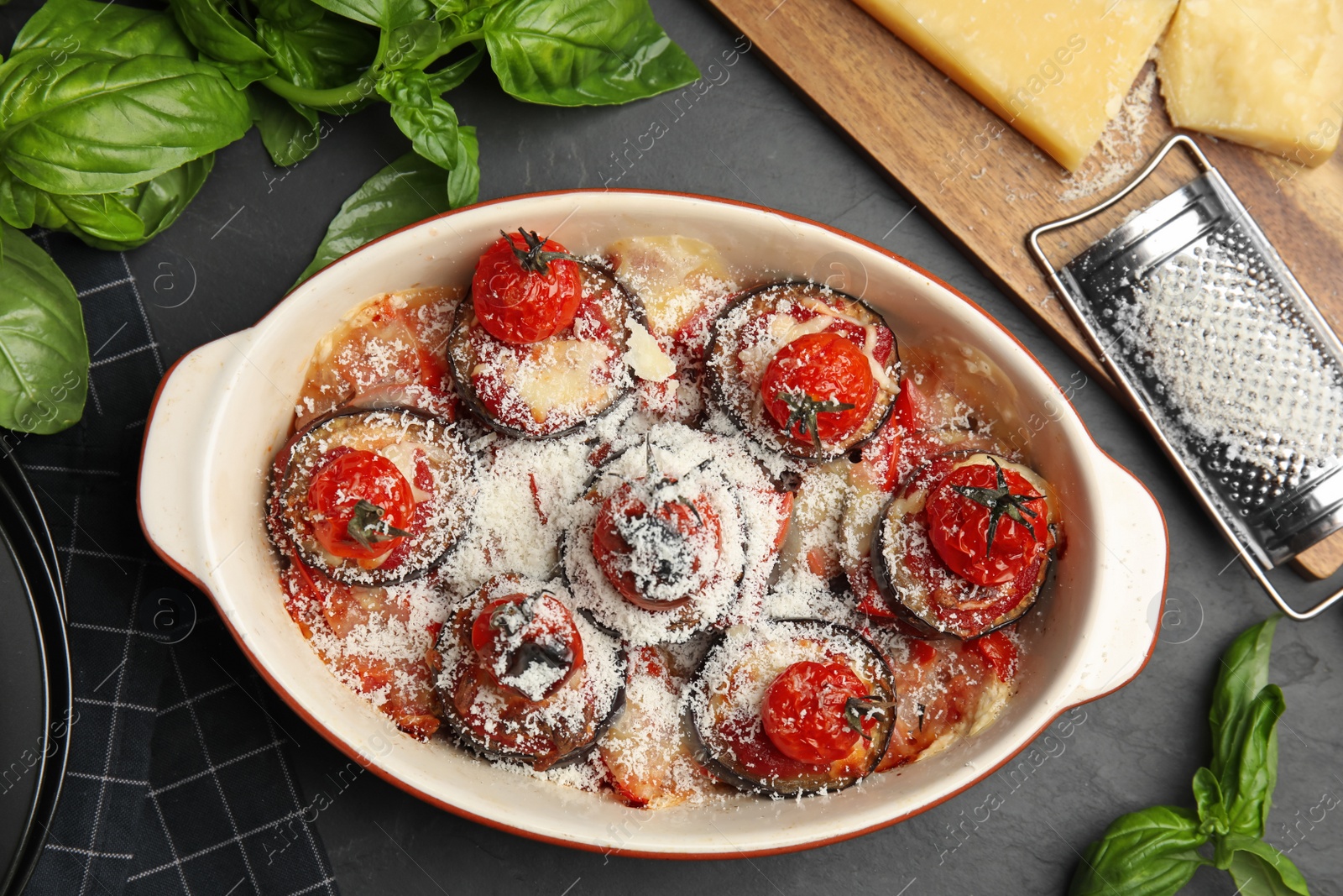Baked eggplant with tomatoes and cheese served on black table, flat lay Photo of Baked eggplant with tomatoes and cheese served on black table, flat lay