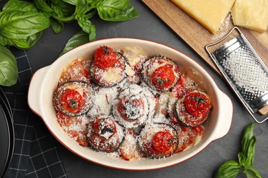 Photo of Baked eggplant with tomatoes and cheese served on black table, flat lay
