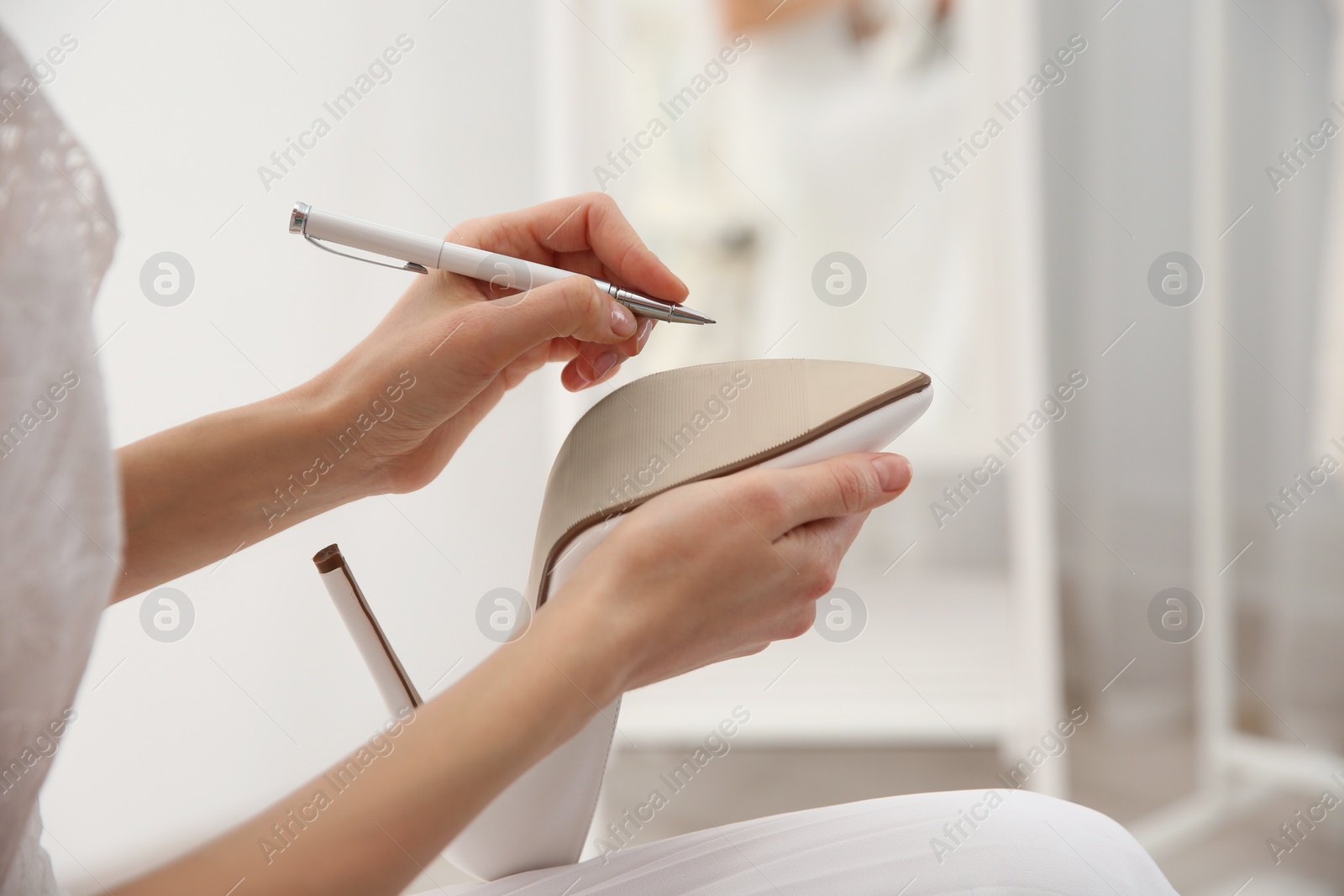 Young bride writing on her shoe indoors, closeup. Wedding superstition Photo of Young bride writing on her shoe indoors, closeup. Wedding superstition