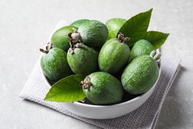 Delicious fresh feijoas in bowl on light grey table, closeup Photo of Delicious fresh feijoas in bowl on light grey table, closeup
