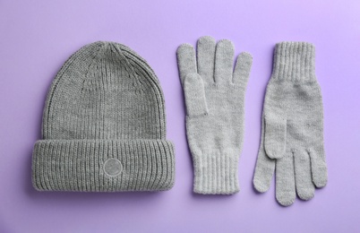 Woolen gloves and hat on violet background, flat lay Photo of Woolen gloves and hat on violet background, flat lay
