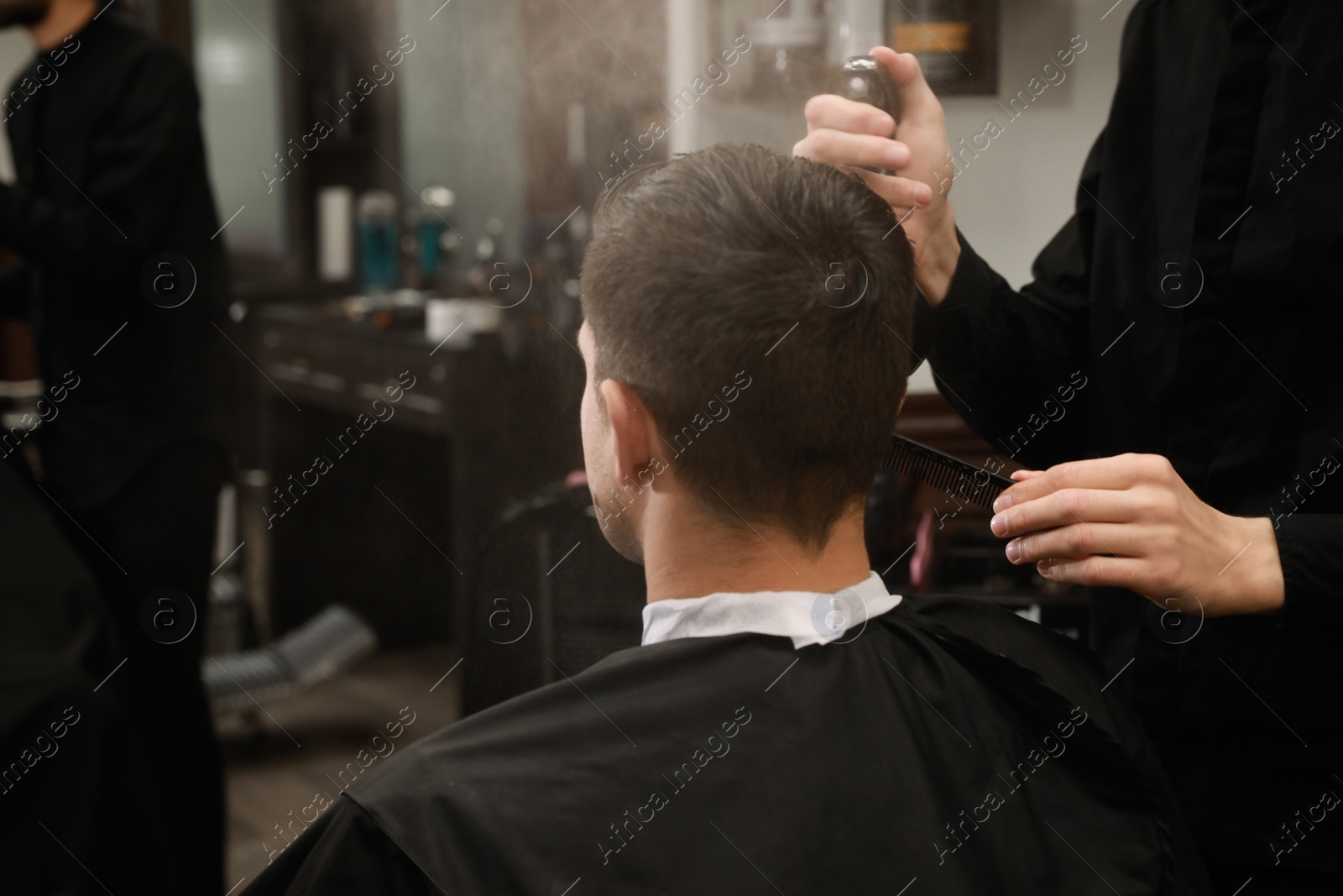 Professional hairdresser making stylish haircut in salon, back view Photo of Professional hairdresser making stylish haircut in salon, back view