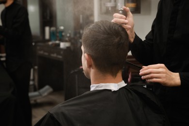 Professional hairdresser making stylish haircut in salon, back view Photo of Professional hairdresser making stylish haircut in salon, back view