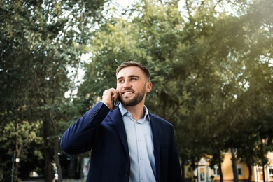Young man talking on smartphone in park Photo of Young man talking on smartphone in park