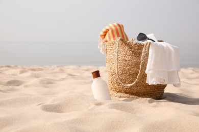 Beach bag, towel, blanket, sunglasses and sunscreen on sandy seashore, space for text Photo of Beach bag, towel, blanket, sunglasses and sunscreen on sandy seashore, space for text