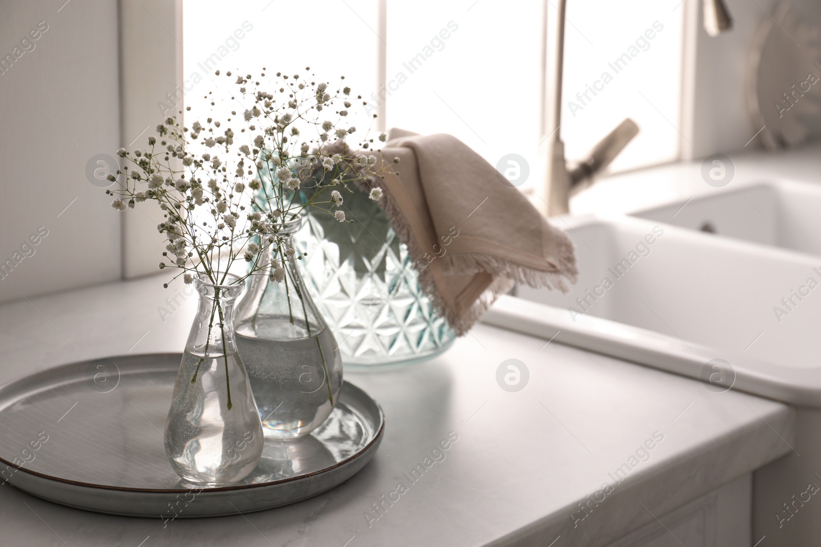 Vases with gypsophila flowers near sink in kitchen, space for text. Interior design Photo of Vases with gypsophila flowers near sink in kitchen, space for text. Interior design