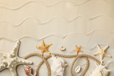 Beautiful sea stars, shells and rope on sand, flat lay. Space for text Photo of Beautiful sea stars, shells and rope on sand, flat lay. Space for text