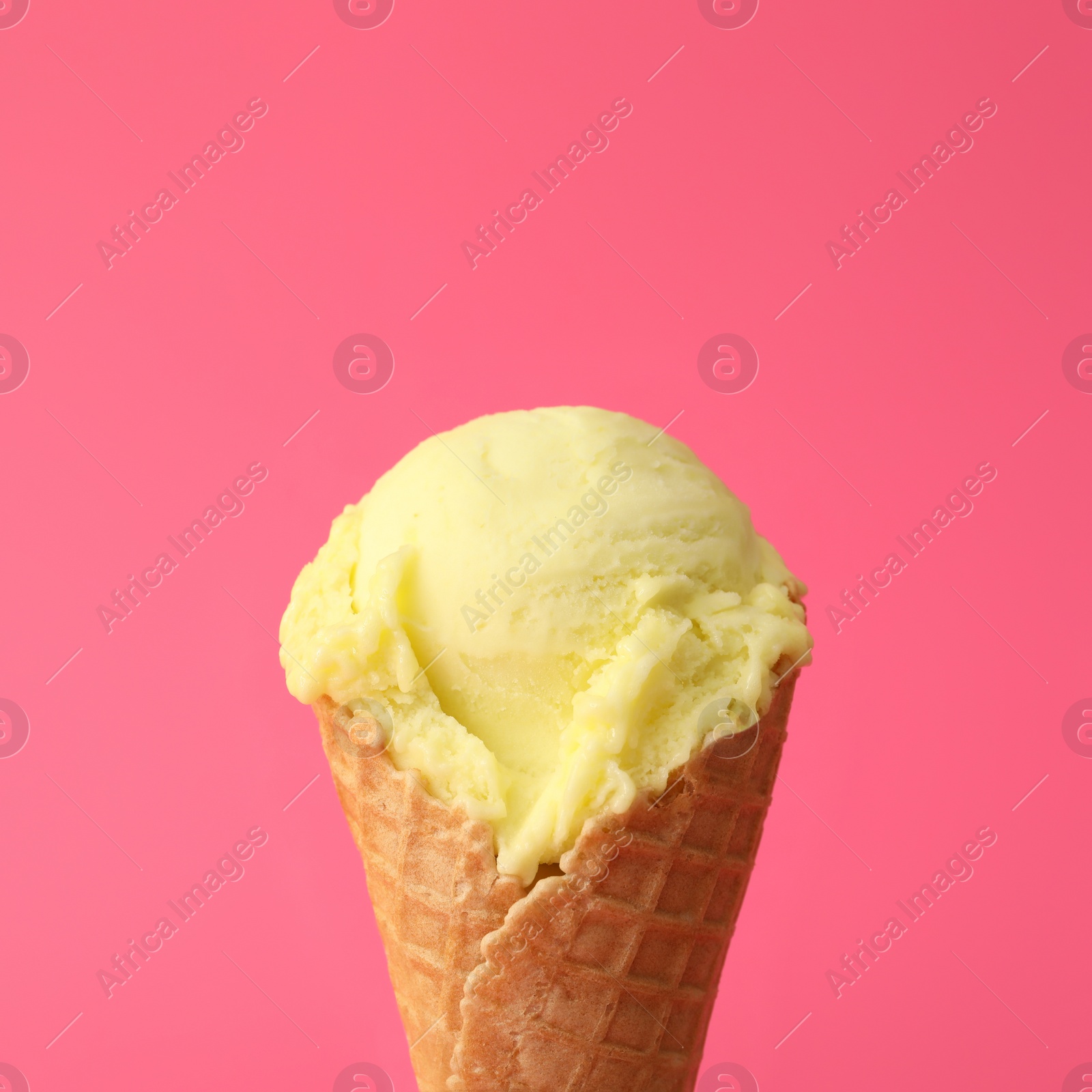 Delicious yellow ice cream in waffle cone on pink background, closeup Photo of Delicious yellow ice cream in waffle cone on pink background, closeup