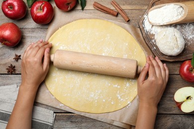 Woman rolling dough for apple pie at wooden table, top view Photo of Woman rolling dough for apple pie at wooden table, top view