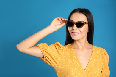 Beautiful woman wearing sunglasses on blue background Photo of Beautiful woman wearing sunglasses on blue background