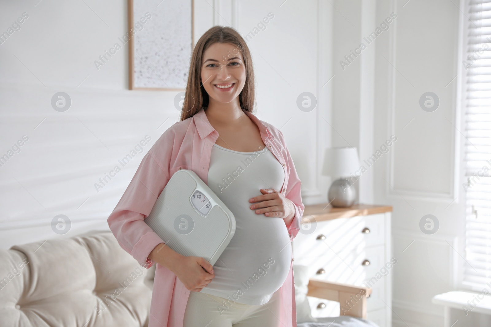 Young pregnant woman with scales at home Photo of Young pregnant woman with scales at home