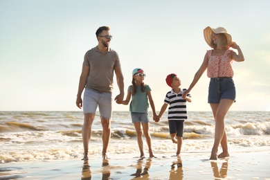 Happy family walking on sandy beach near sea Photo of Happy family walking on sandy beach near sea