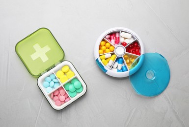 Plastic boxes with different pills on light grey stone table, flat lay Photo of Plastic boxes with different pills on light grey stone table, flat lay