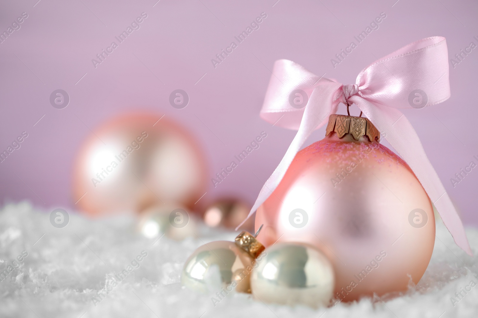 Beautiful Christmas balls on snow against pink background. Space for text Photo of Beautiful Christmas balls on snow against pink background. Space for text