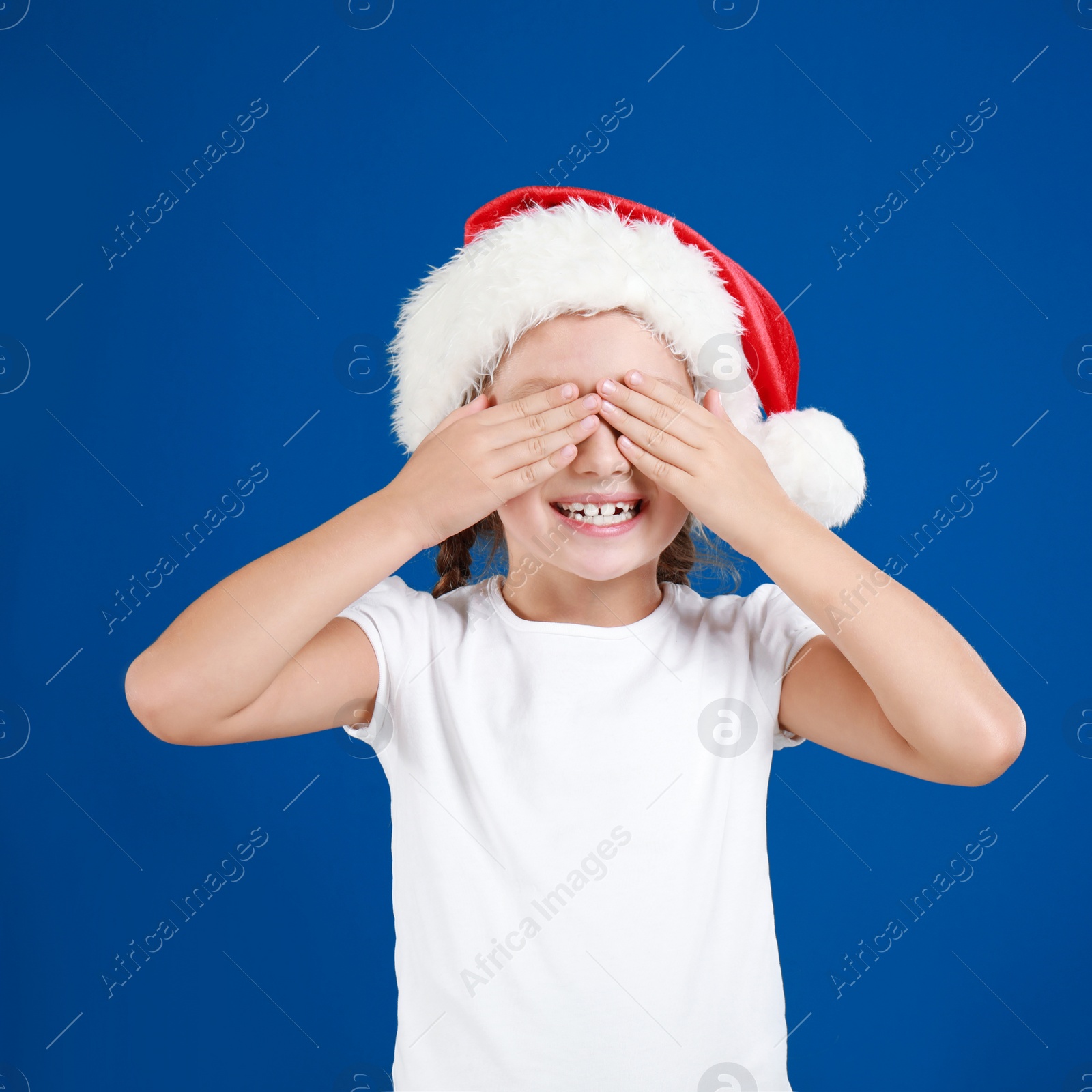 Happy little child in Santa hat closing eyes on blue background. Christmas celebration Image of Happy little child in Santa hat closing eyes on blue background. Christmas celebration