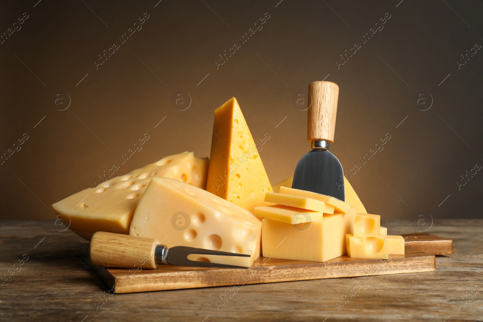 Different sorts of cheese, fork and knife on wooden table Photo of Different sorts of cheese, fork and knife on wooden table