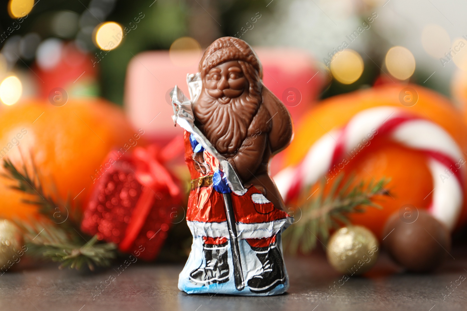Chocolate Santa Claus candy against Christmas decorations, sweets and tangerine fruits Photo of Chocolate Santa Claus candy against Christmas decorations, sweets and tangerine fruits