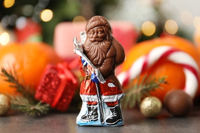 Chocolate Santa Claus candy against Christmas decorations, sweets and tangerine fruits Photo of Chocolate Santa Claus candy against Christmas decorations, sweets and tangerine fruits