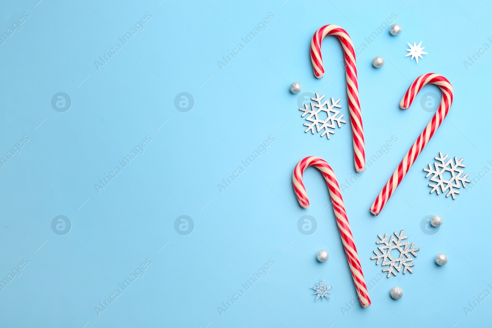 Candy canes and snowflakes on light blue background, flat lay with space for text. Christmas treat Photo of Candy canes and snowflakes on light blue background, flat lay with space for text. Christmas treat