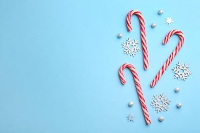 Candy canes and snowflakes on light blue background, flat lay with space for text. Christmas treat Photo of Candy canes and snowflakes on light blue background, flat lay with space for text. Christmas treat