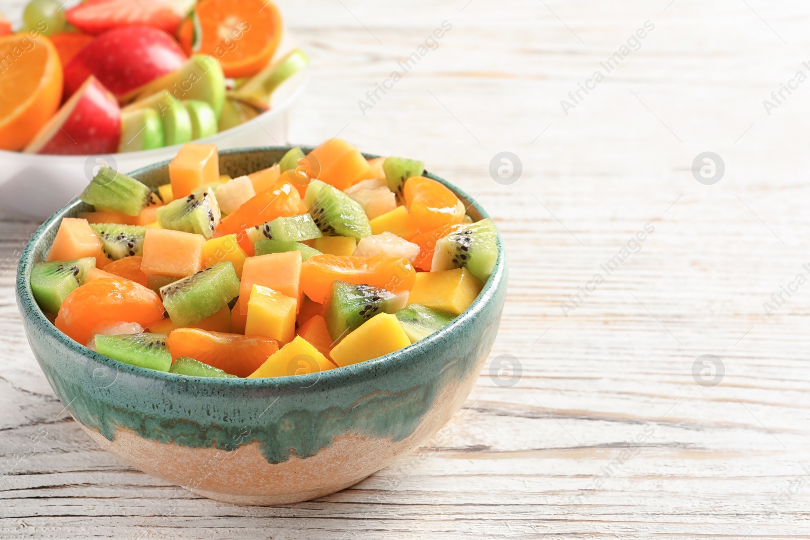 Bowl with fresh cut fruits on wooden table Photo of Bowl with fresh cut fruits on wooden table