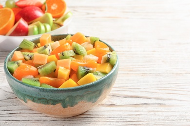 Bowl with fresh cut fruits on wooden table Photo of Bowl with fresh cut fruits on wooden table