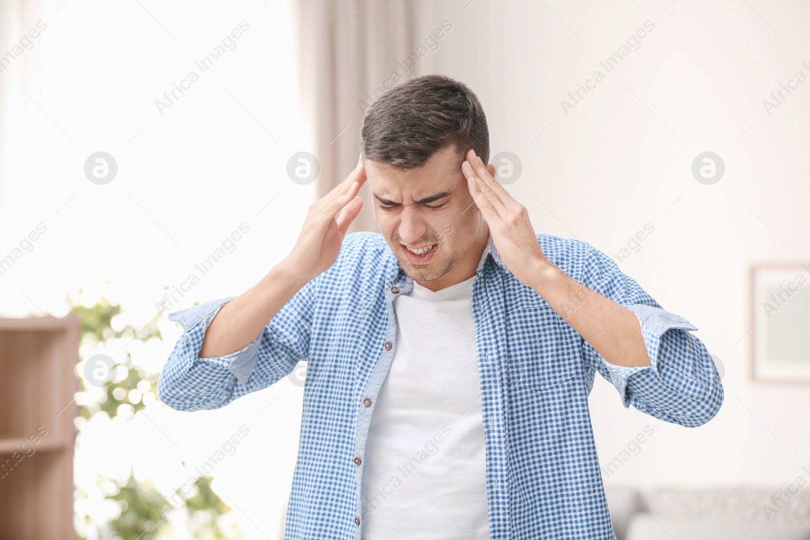 Young man suffering from headache at home Photo of Young man suffering from headache at home