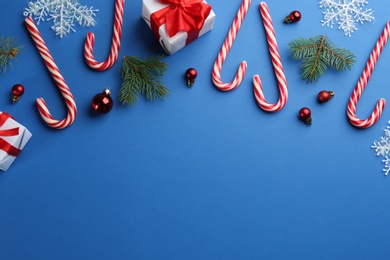 Flat lay composition with candy canes and Christmas decor on blue background. Space for text Photo of Flat lay composition with candy canes and Christmas decor on blue background. Space for text