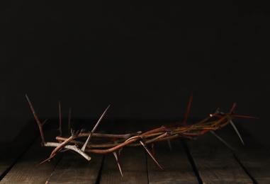 Crown of thorns on wooden table against dark background, space for text. Easter attribute Photo of Crown of thorns on wooden table against dark background, space for text. Easter attribute