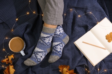 Photo of Woman wearing knitted socks on warm plaid, top view. Cozy season