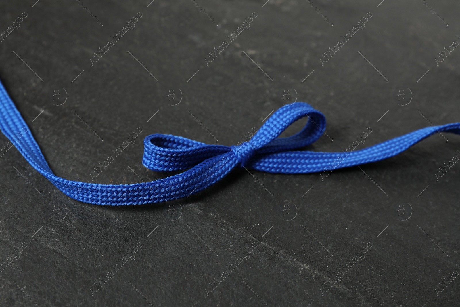 Blue shoelace on black slate background. Stylish accessory Photo of Blue shoelace on black slate background. Stylish accessory