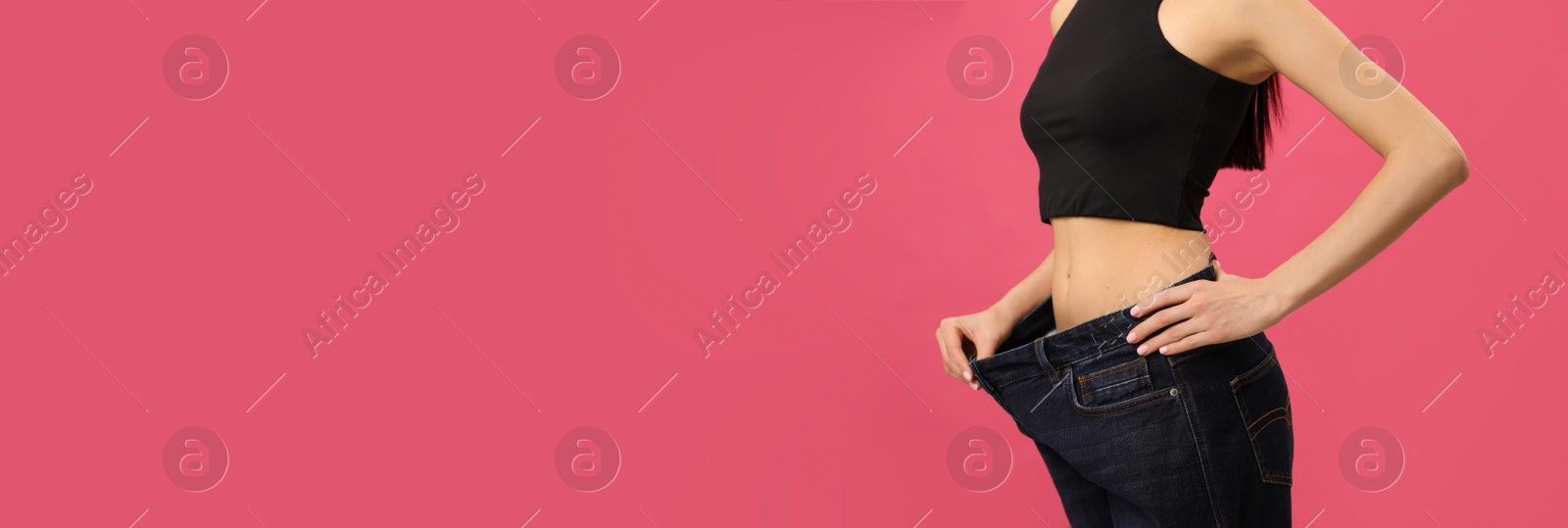 Young woman wearing big jeans after weight loss on pink background, closeup Photo of Young woman wearing big jeans after weight loss on pink background, closeup