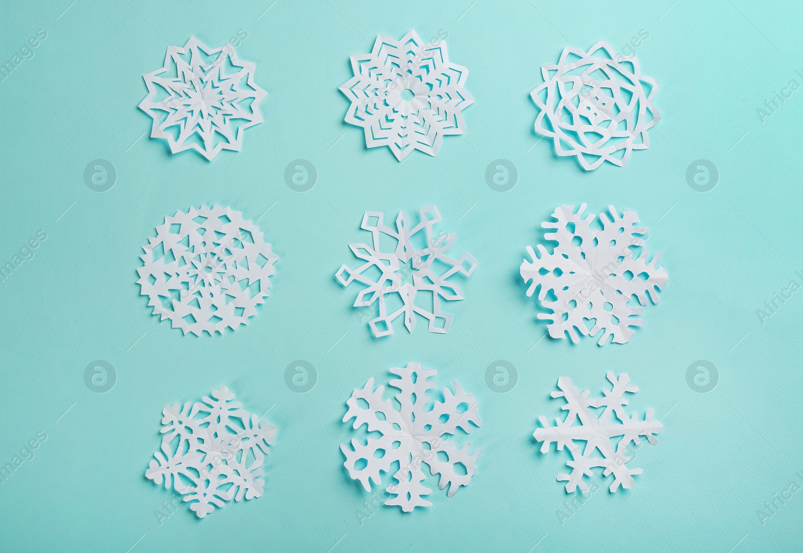 Flat lay composition with paper snowflakes on cyan background Photo of Flat lay composition with paper snowflakes on cyan background