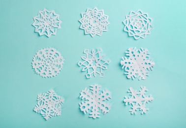 Flat lay composition with paper snowflakes on cyan background Photo of Flat lay composition with paper snowflakes on cyan background