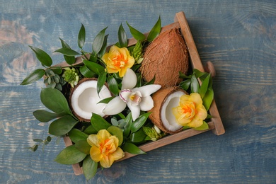 Box with coconuts and flowers on wooden background Photo of Box with coconuts and flowers on wooden background