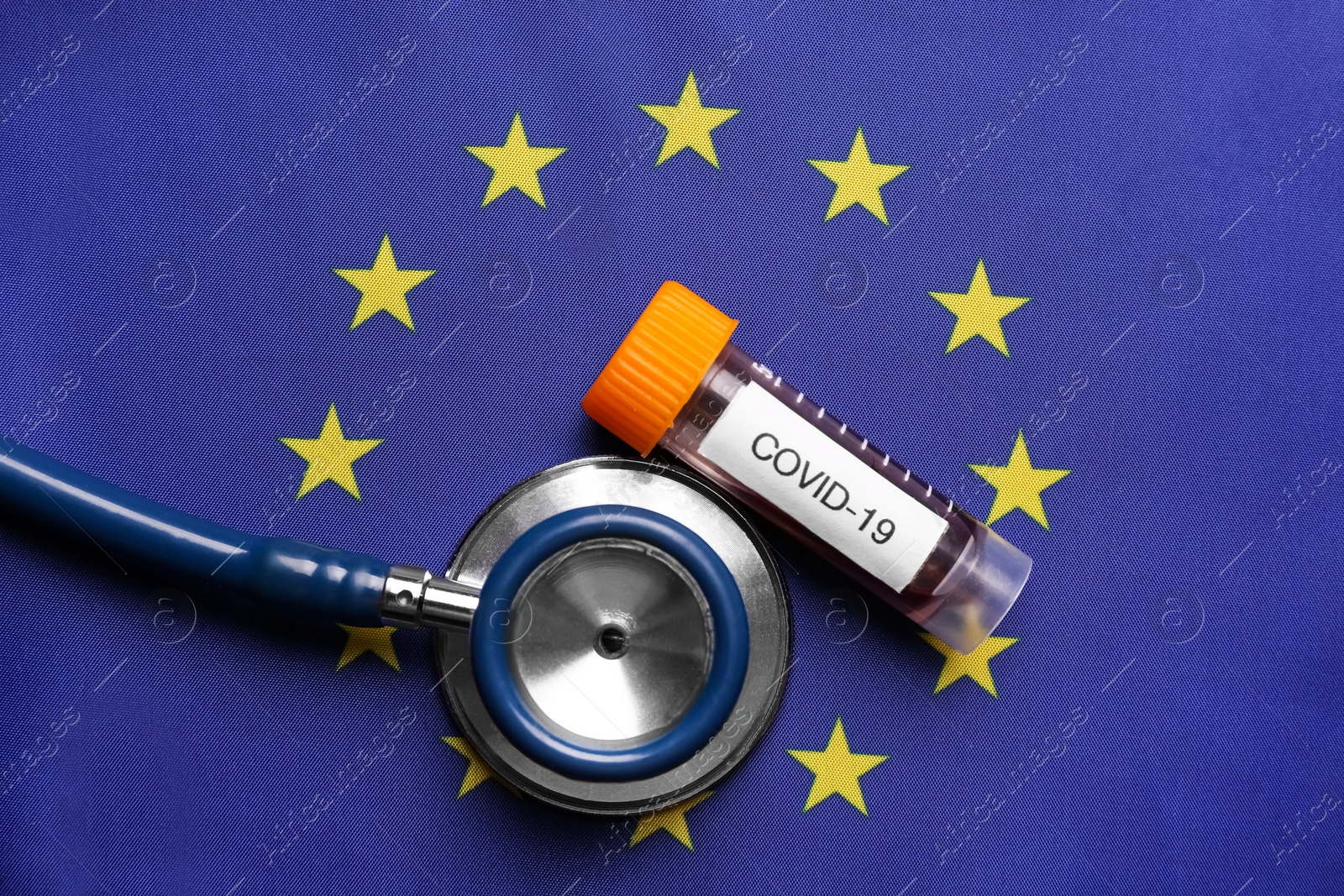 Stethoscope and test tube with blood sample on European Union flag background, flat lay. Coronavirus outbreak Photo of Stethoscope and test tube with blood sample on European Union flag background, flat lay. Coronavirus outbreak