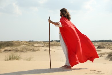Jesus Christ walking with stick in desert. Space for text Photo of Jesus Christ walking with stick in desert. Space for text