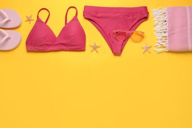 Stylish bikini and beach accessories on yellow background, flat lay. Space for text Photo of Stylish bikini and beach accessories on yellow background, flat lay. Space for text