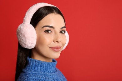 Beautiful young woman wearing earmuffs on red background. Space for text Photo of Beautiful young woman wearing earmuffs on red background. Space for text