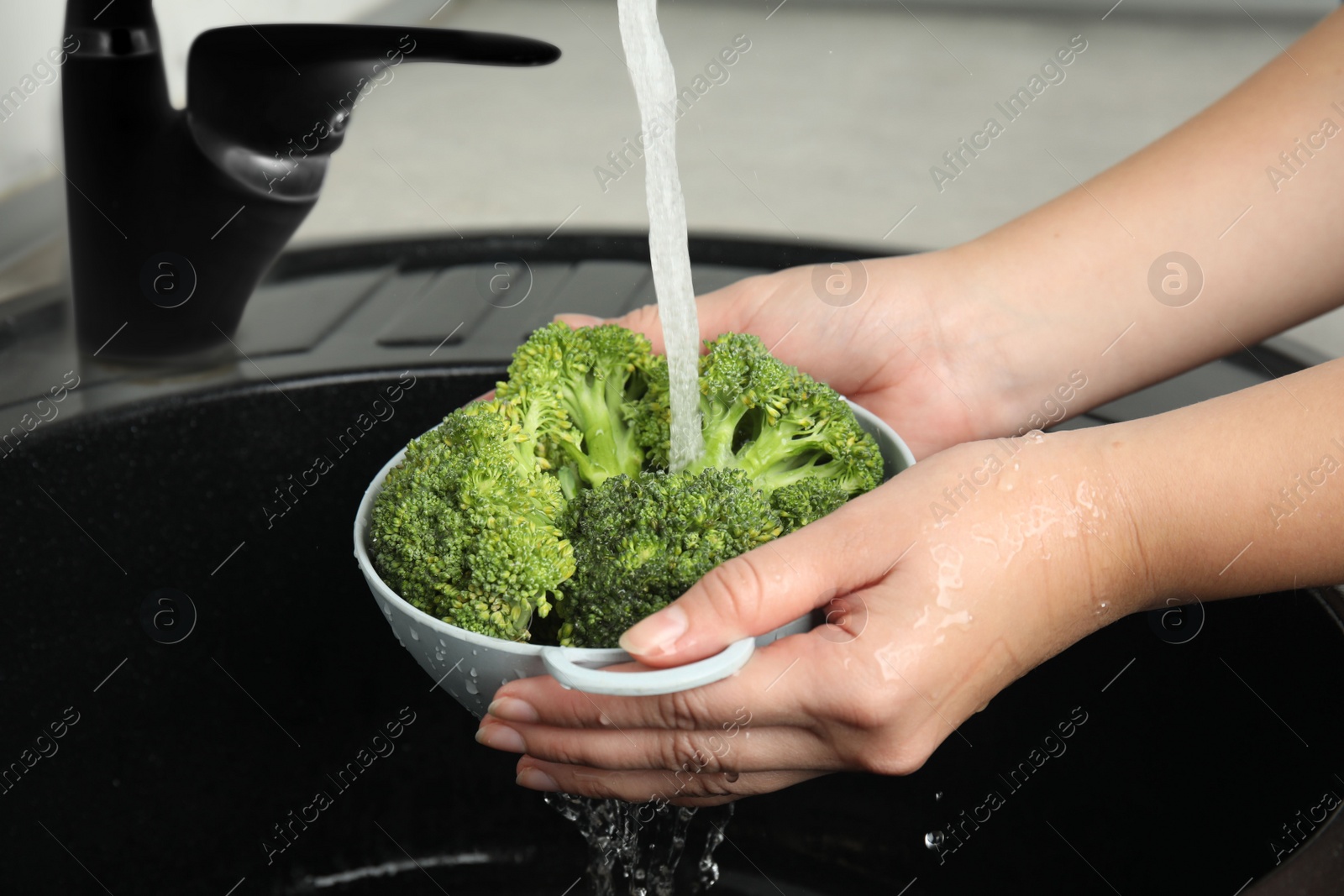 Woman washing fresh green broccoli in kitchen sink, closeup Photo of Woman washing fresh green broccoli in kitchen sink, closeup