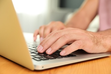 Man using laptop for search at wooden table indoors, closeup Photo of Man using laptop for search at wooden table indoors, closeup