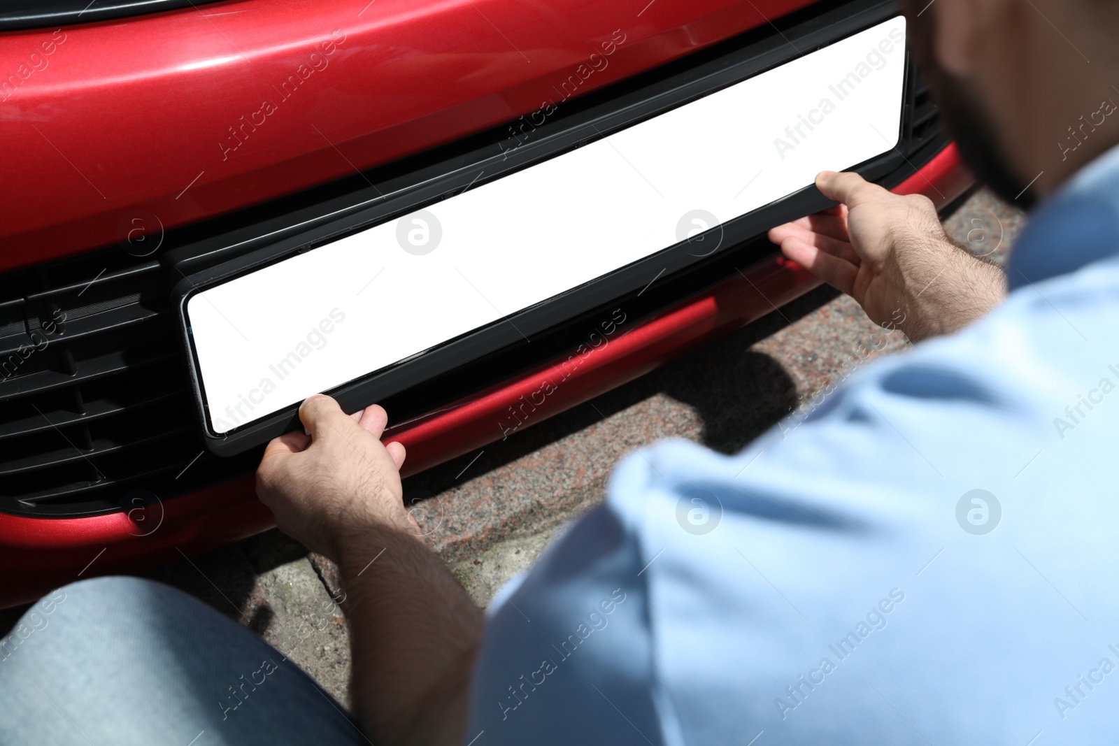 Man installing vehicle registration plate outdoors, closeup. Mockup for design Photo of Man installing vehicle registration plate outdoors, closeup. Mockup for design