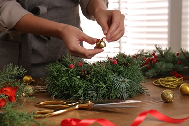 Florist making beautiful Christmas wreath at wooden table indoors, closeup Photo of Florist making beautiful Christmas wreath at wooden table indoors, closeup