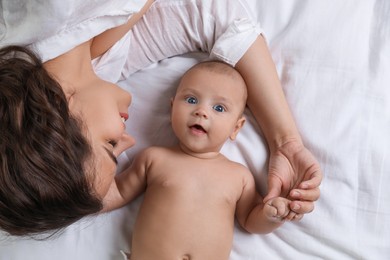Happy young mother with her cute baby on bed, top view Photo of Happy young mother with her cute baby on bed, top view